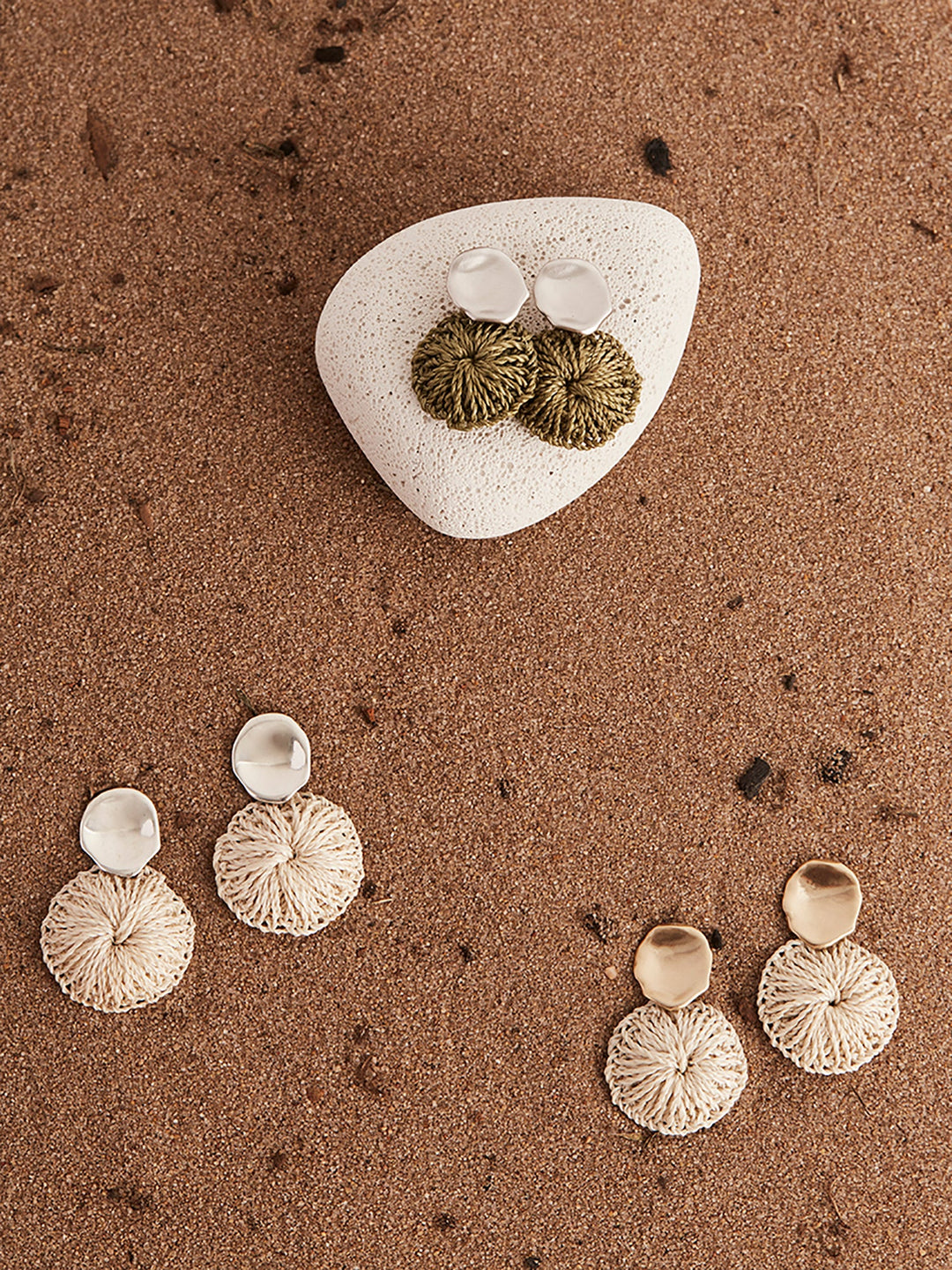 Handwoven natural fibre disc earrings on a stone flat lay still life.
