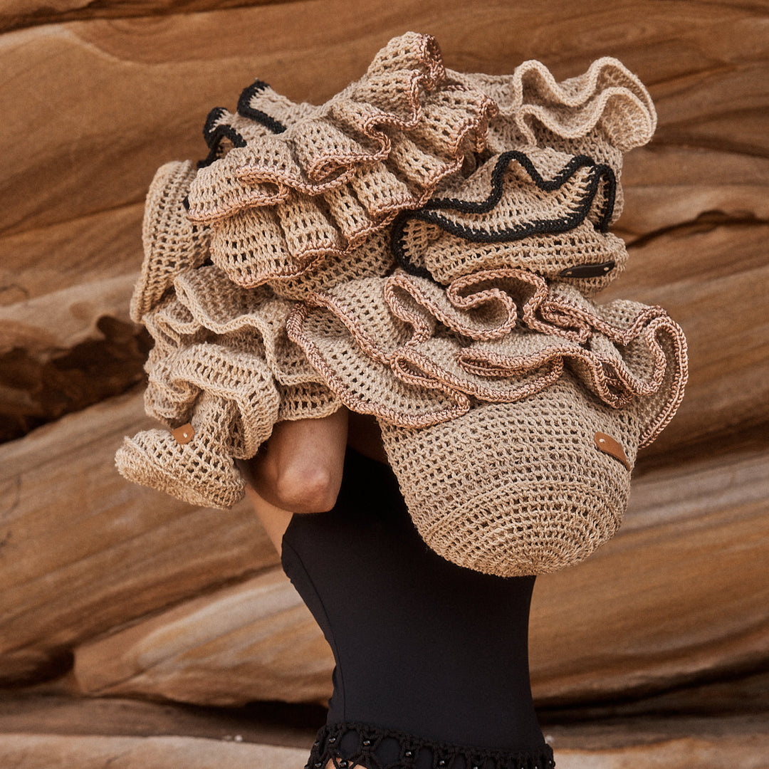 Artistic shot of model holding a collection of natural fibre bilum bags with ruffle embellishments.