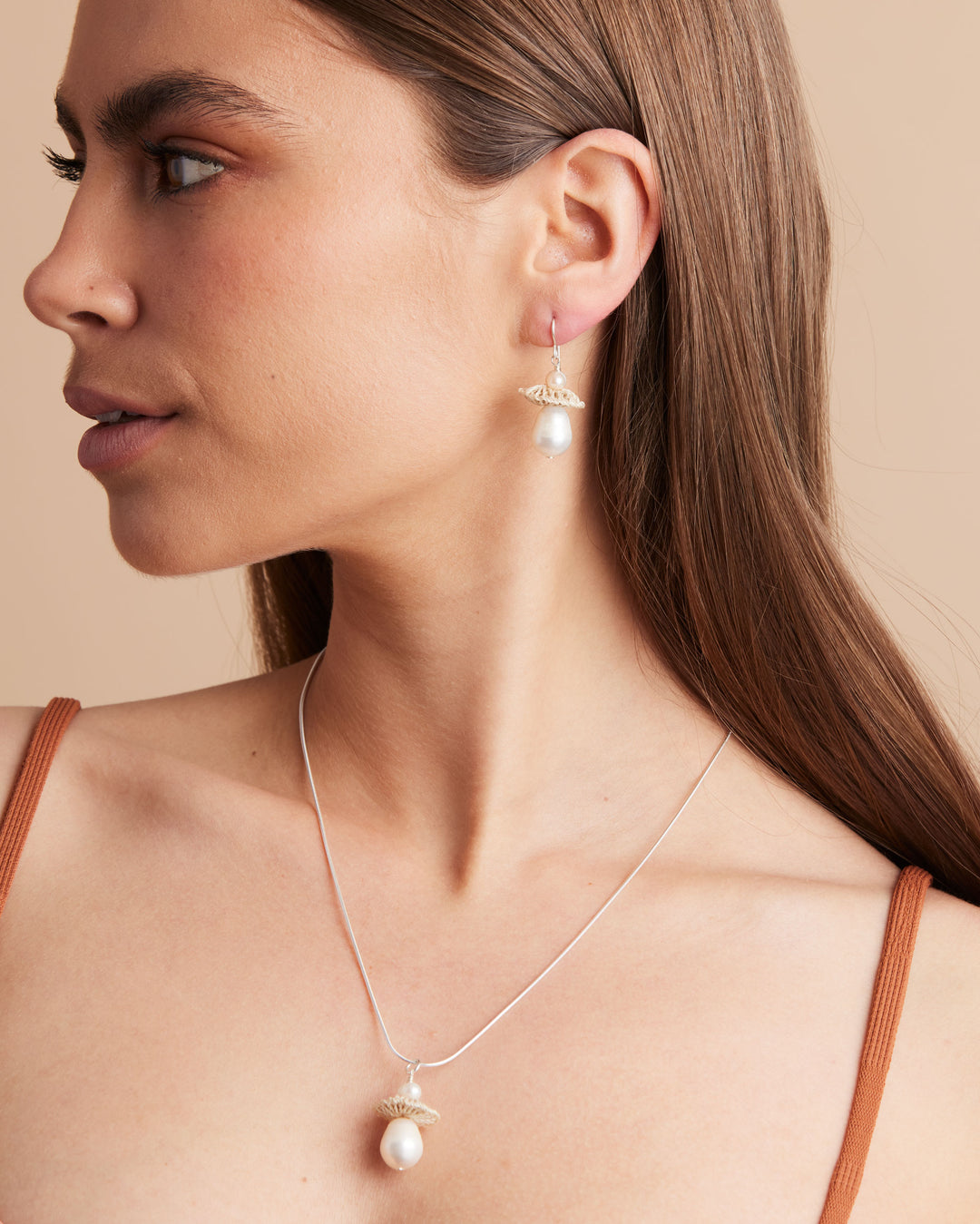 Model wearing silver chain with natural fibre and pearl pendant