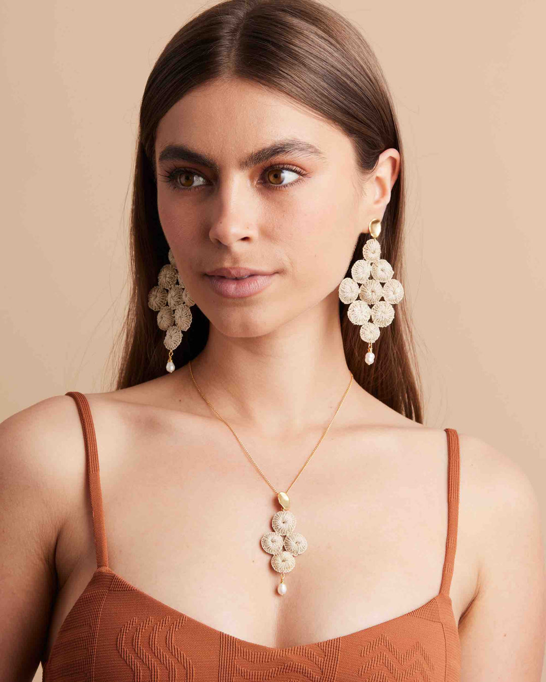Model wearing bilum and bilas statement earrings and necklace in a brown top