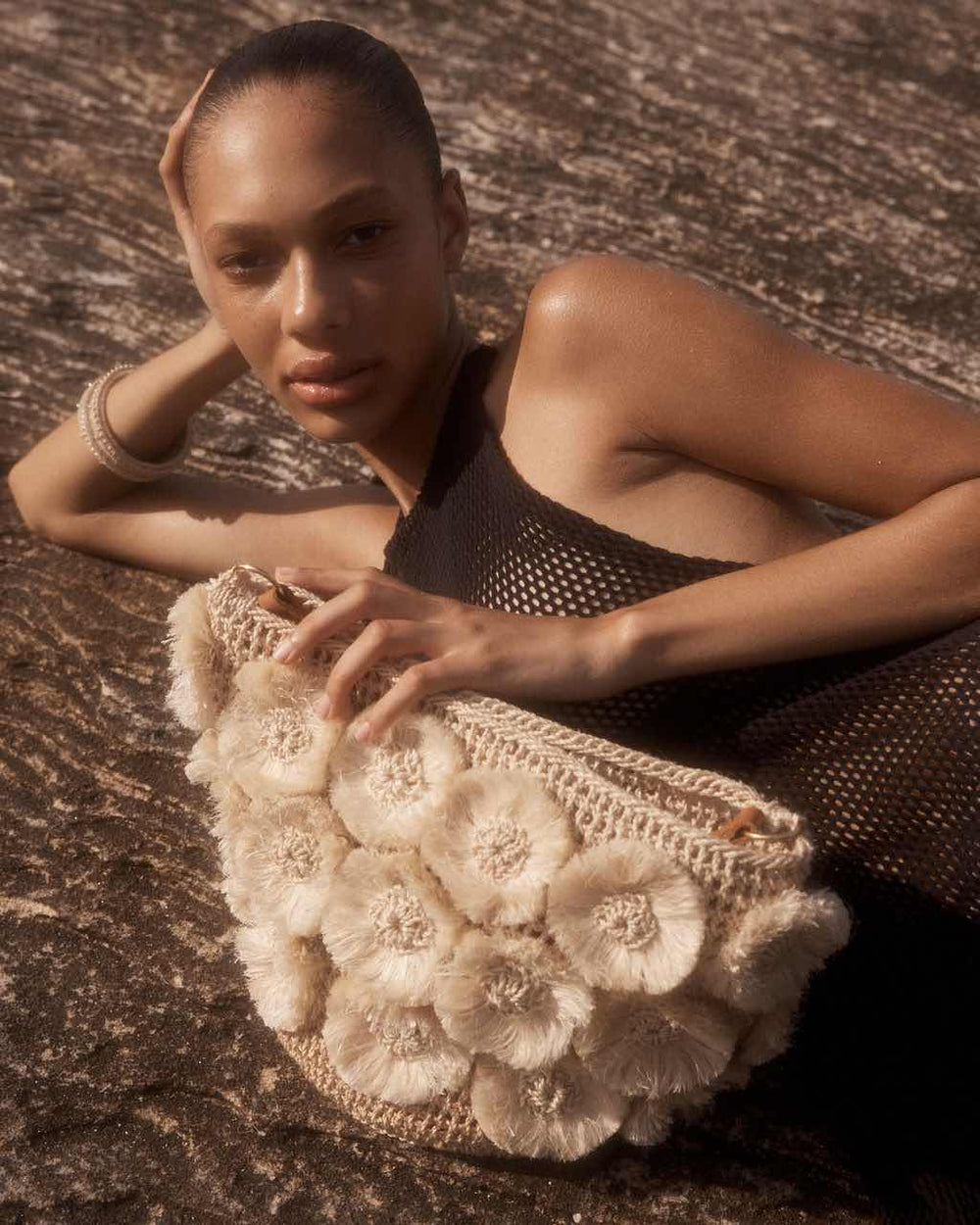 Model posing on rocks with bilum and bilas Kalea Basket Bucket bilum