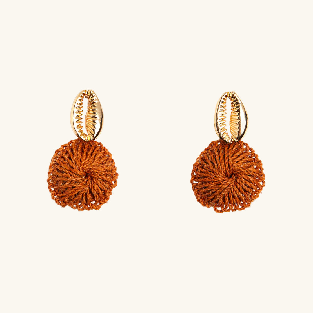 Pair of earrings with gold hooks and orange spherical pendants on a white background