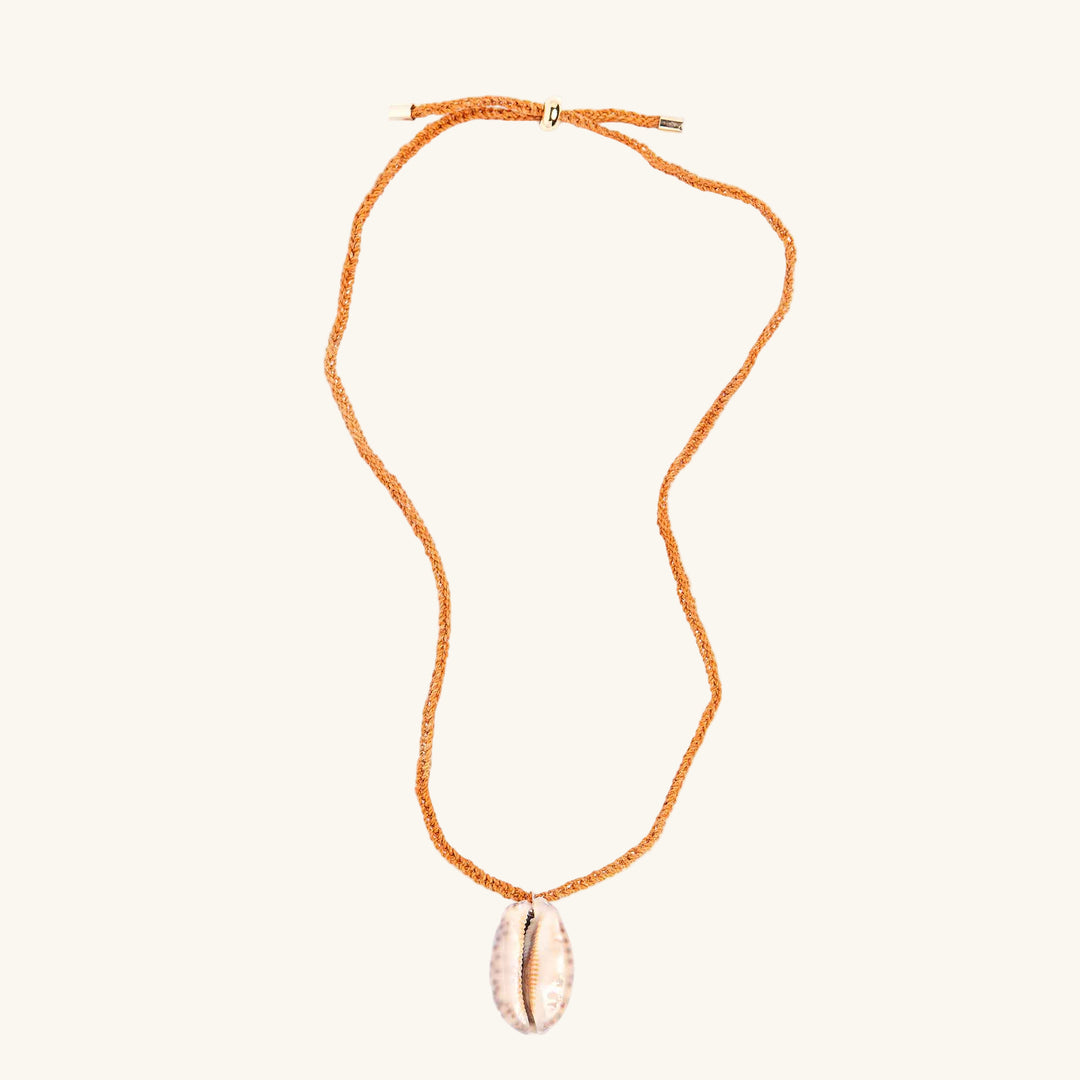Necklace with a shell pendant on an orange cord against a white background