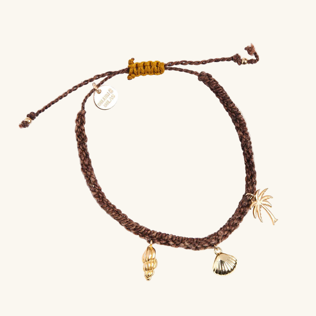 Brown braided bracelet with gold charms on a white background