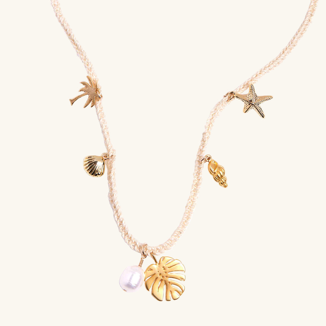 Gold necklace with various sea-themed charms on a white background