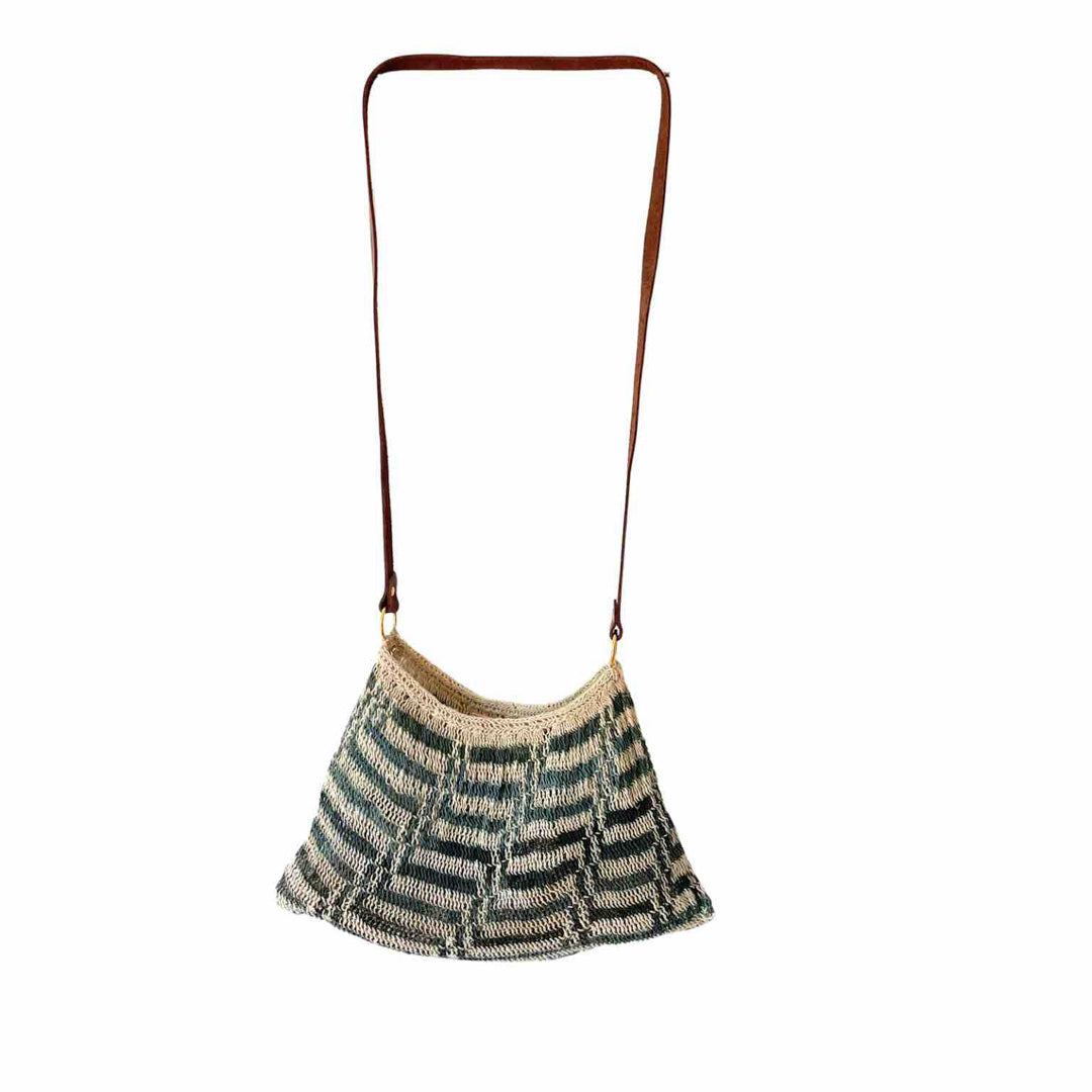 Blue and white bilum with leather strap hanging on white background