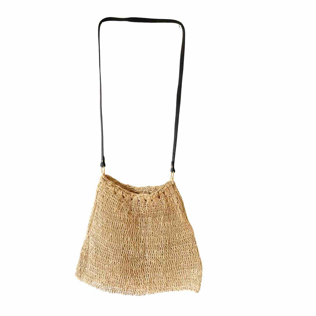 Plain natural fibre bilum with leather strap hanging on a white background.
