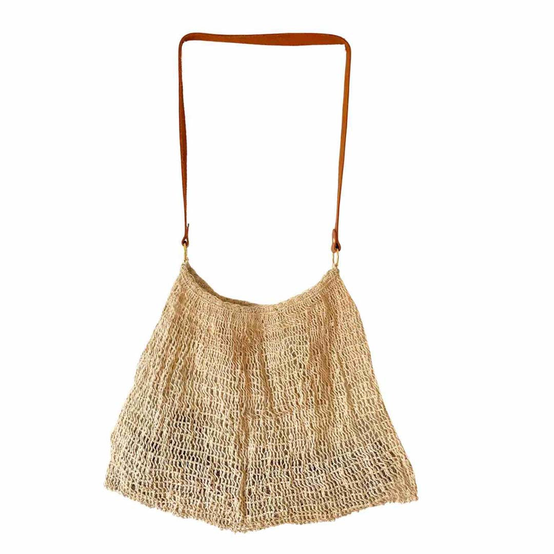 Natural fibre plain bilum with leather strap hanging on a white background.