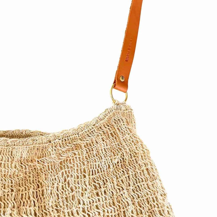 Close up on the leather strap of a natural fibre bilum with leather strap.