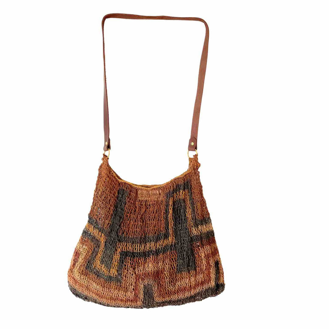 Rich earth toned bilum with leather strap hanging on a white background.