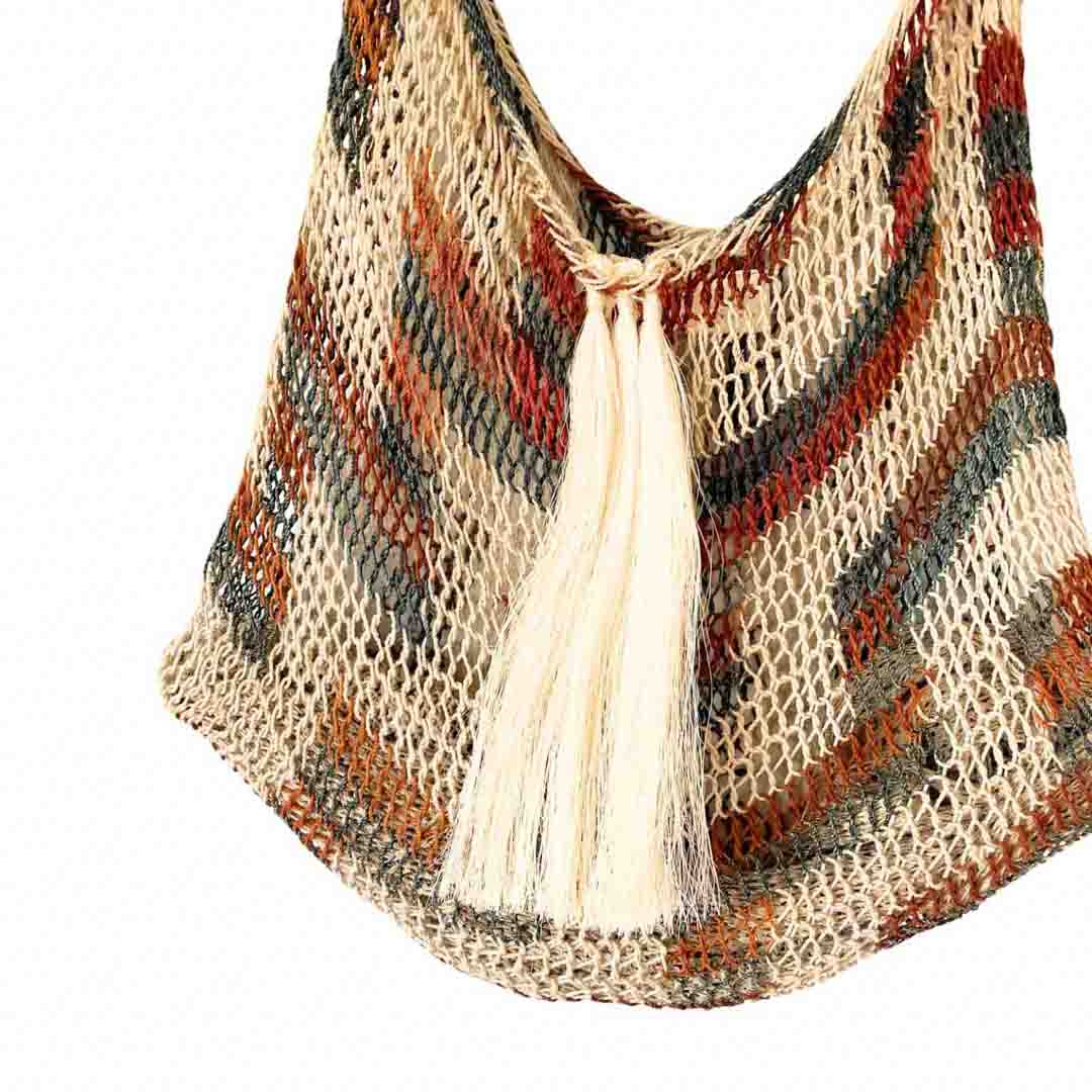 Natural bilum with tassels and a leather strap detail on weave and adornment.