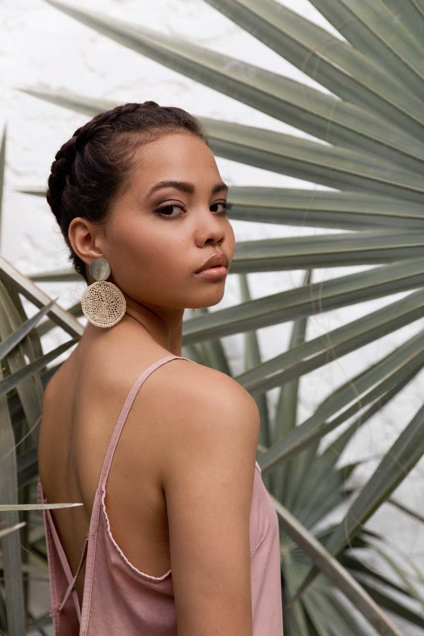 Model wearing Bilum and Bilas boho chic statement earrings in a tropical scene