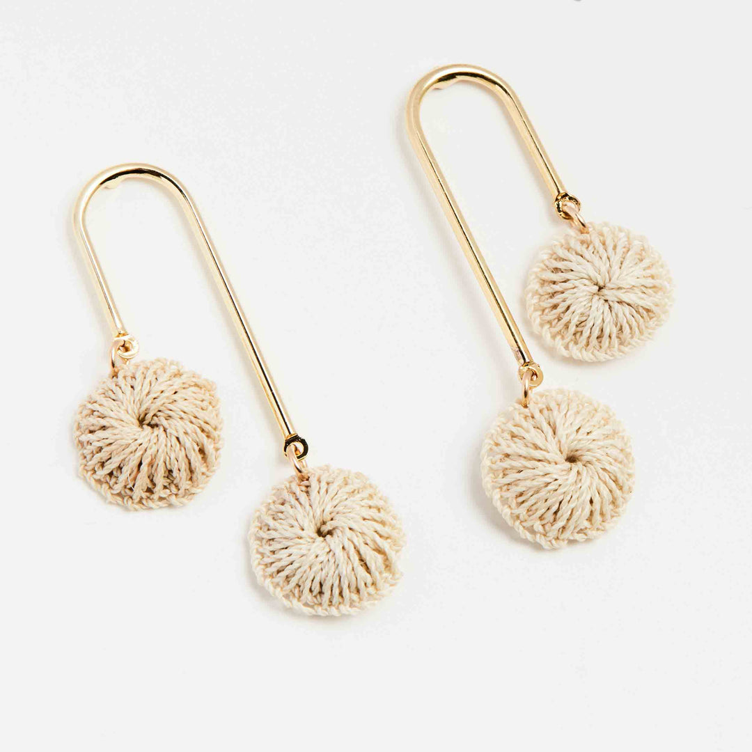 Bilum and Bilas gold arched earrings with dangling natural fibre discs angled view