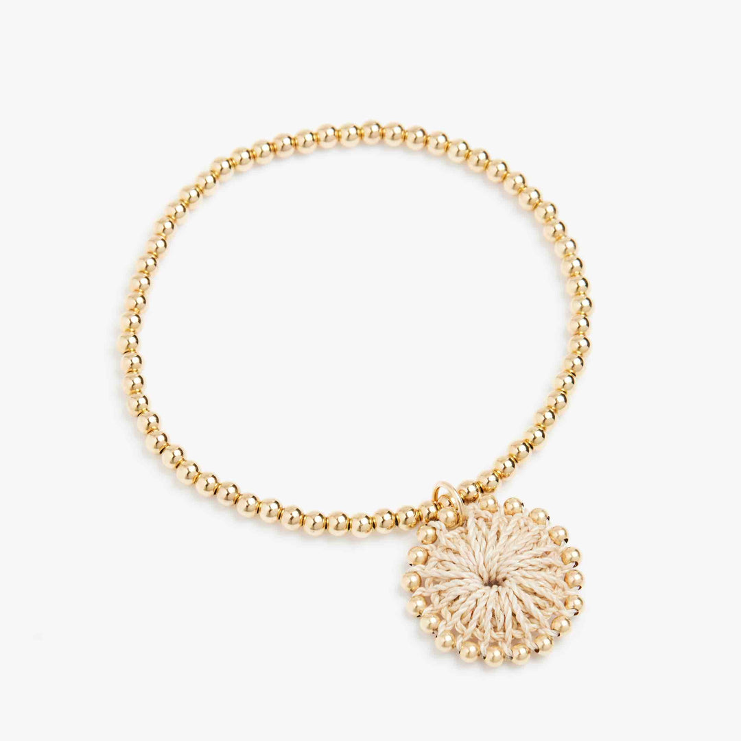 Gold beaded bracelet with natural fibre woven charm left angle