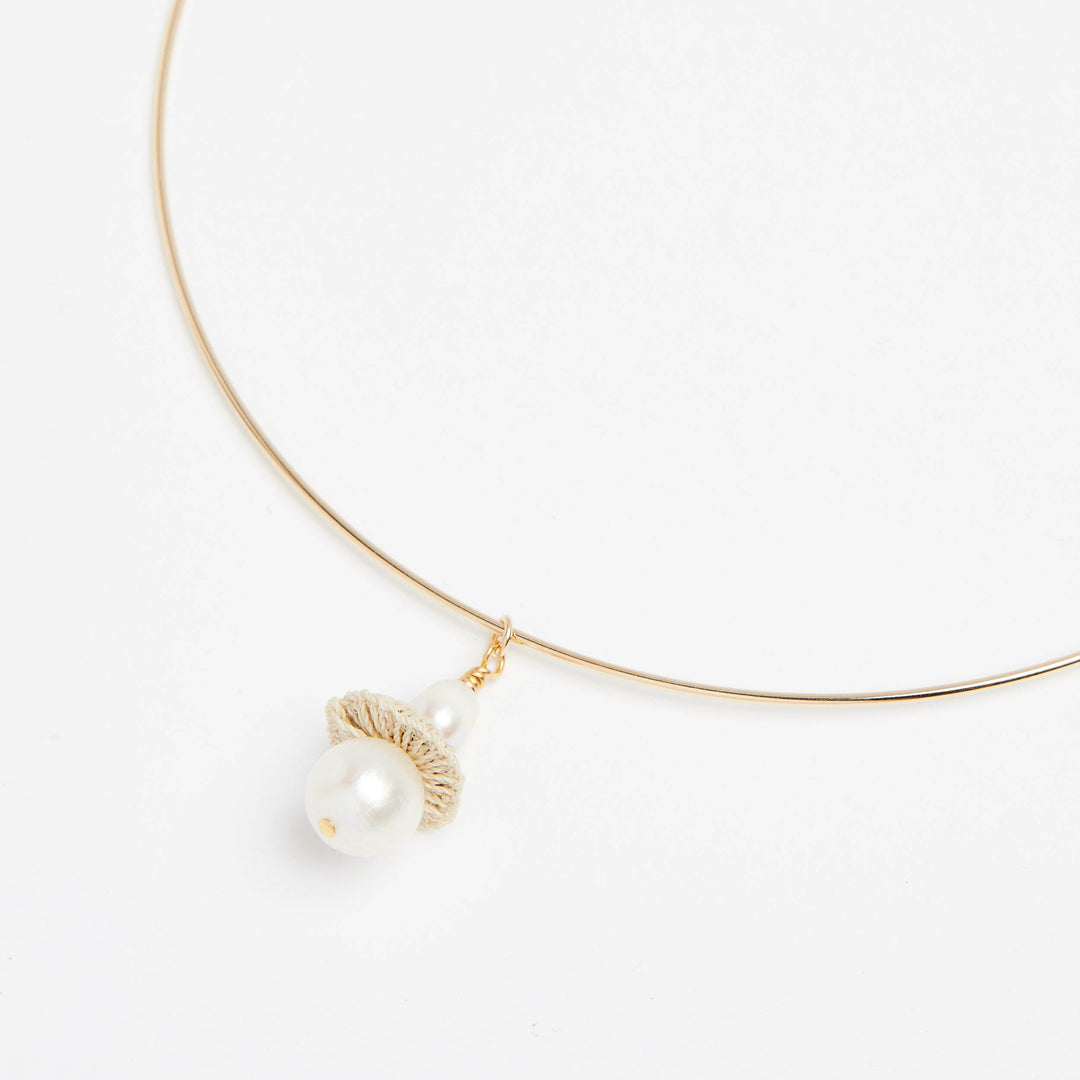 Side angle of gold filled choker pendant with pearl and woven natural fibre disc