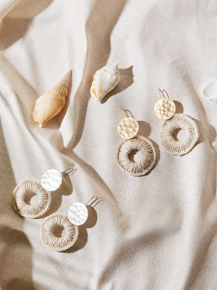 Bilum and Bilas gold and silver disc earrings with natural fibre woven hoop earrings displayed on linen with shells