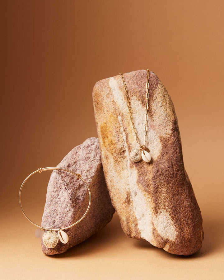 Still life on rock with Bilum and Bilas gold filled adjustable bracelet with shell and natural fibre charms and matching necklace