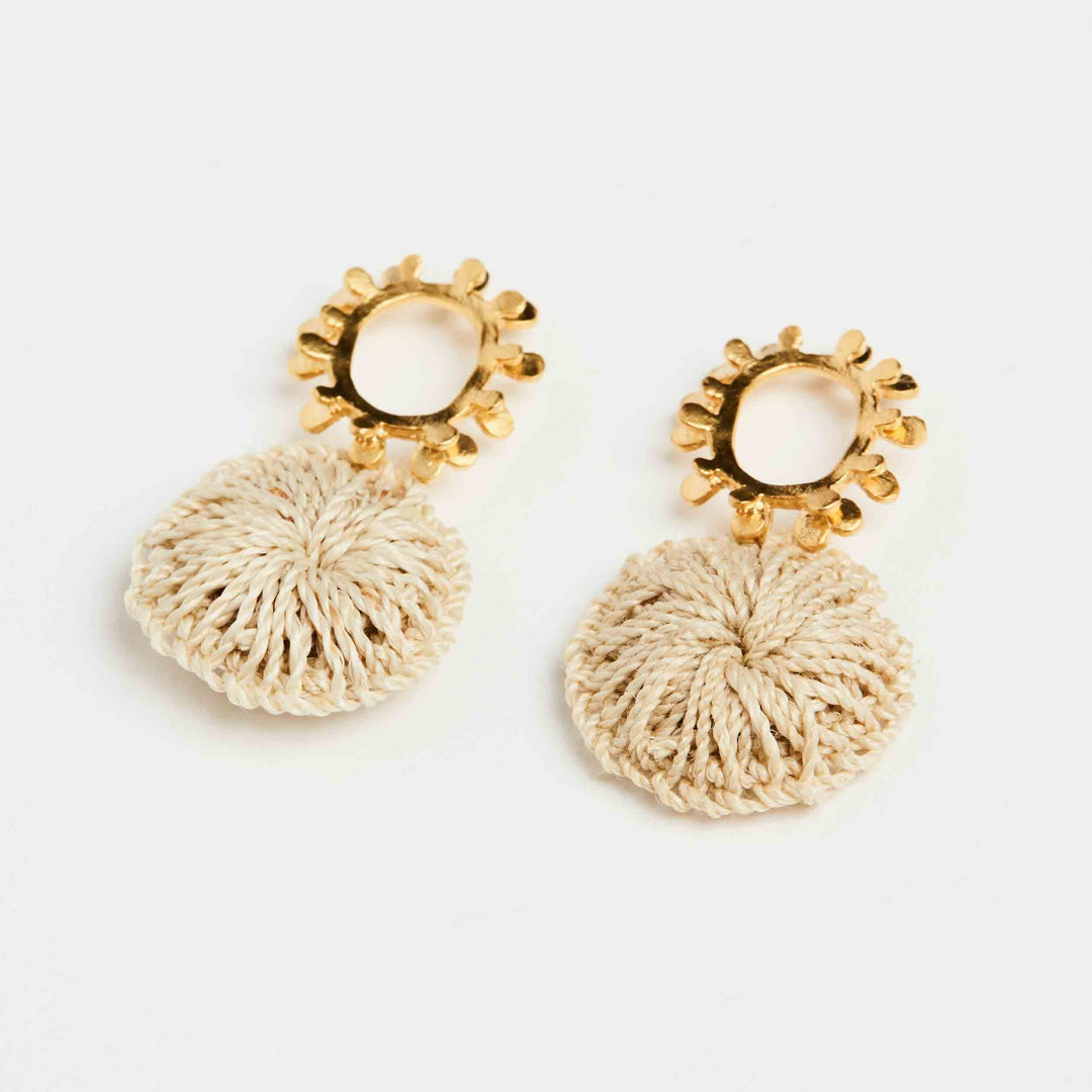 Angled view of gold textured sun earrings with natural fibre woven discs