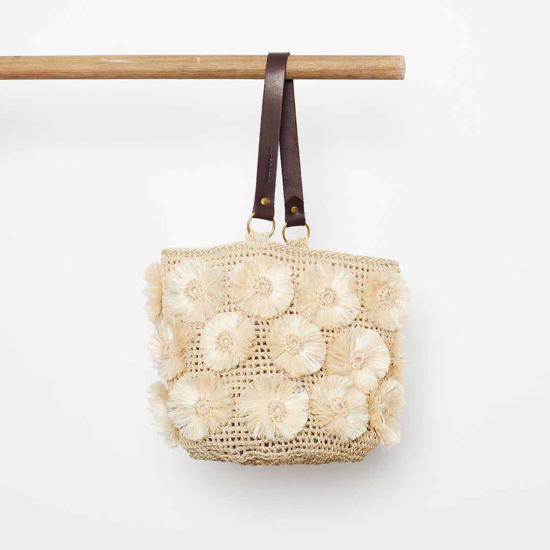 Handwoven natural basket with handmade flower embellishments on white background
