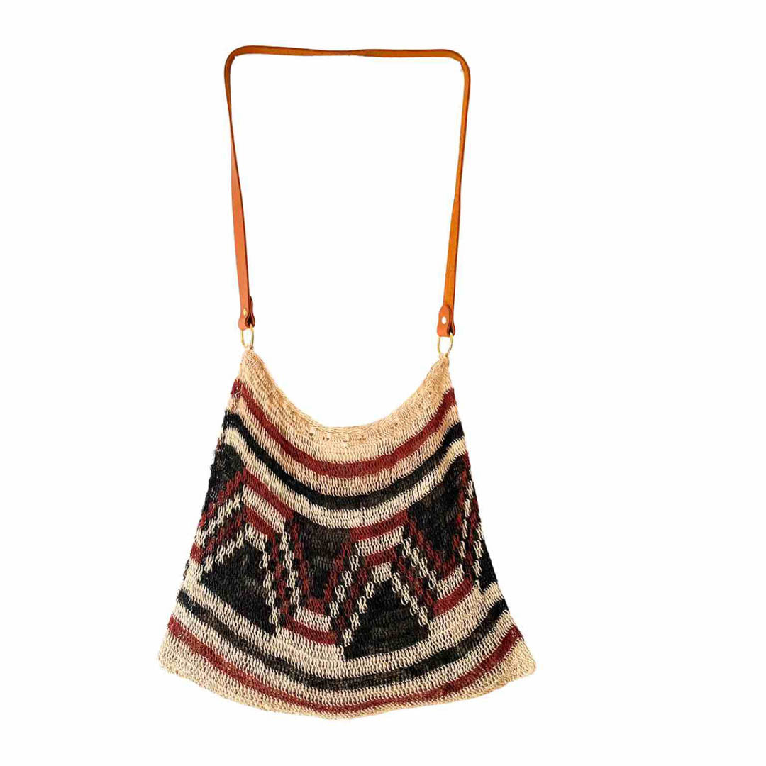 Brown patterned bilum with leather strap hanging on white background.
