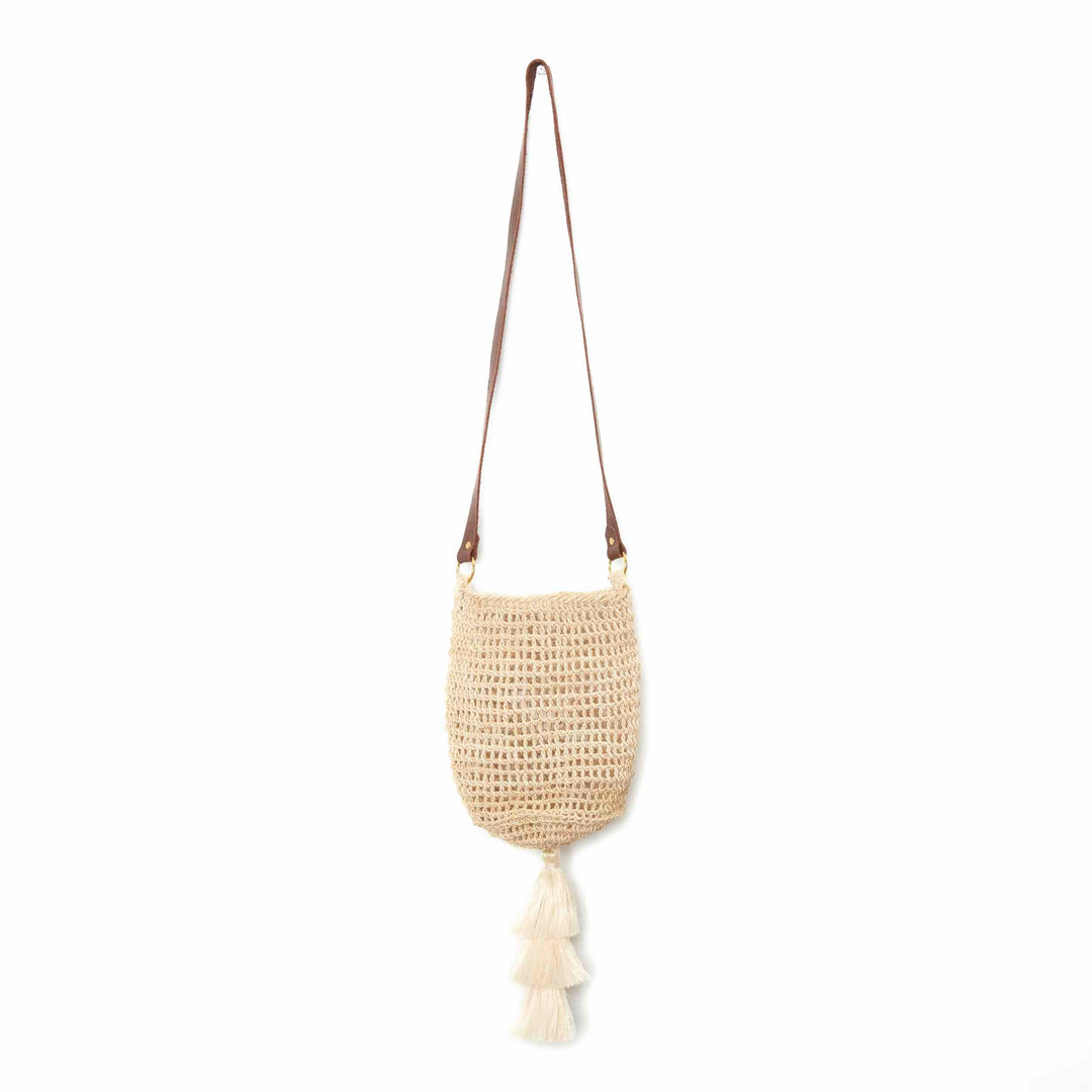 Natural bucket bilum bag with leather strap and tassel on base hanging on a white background.