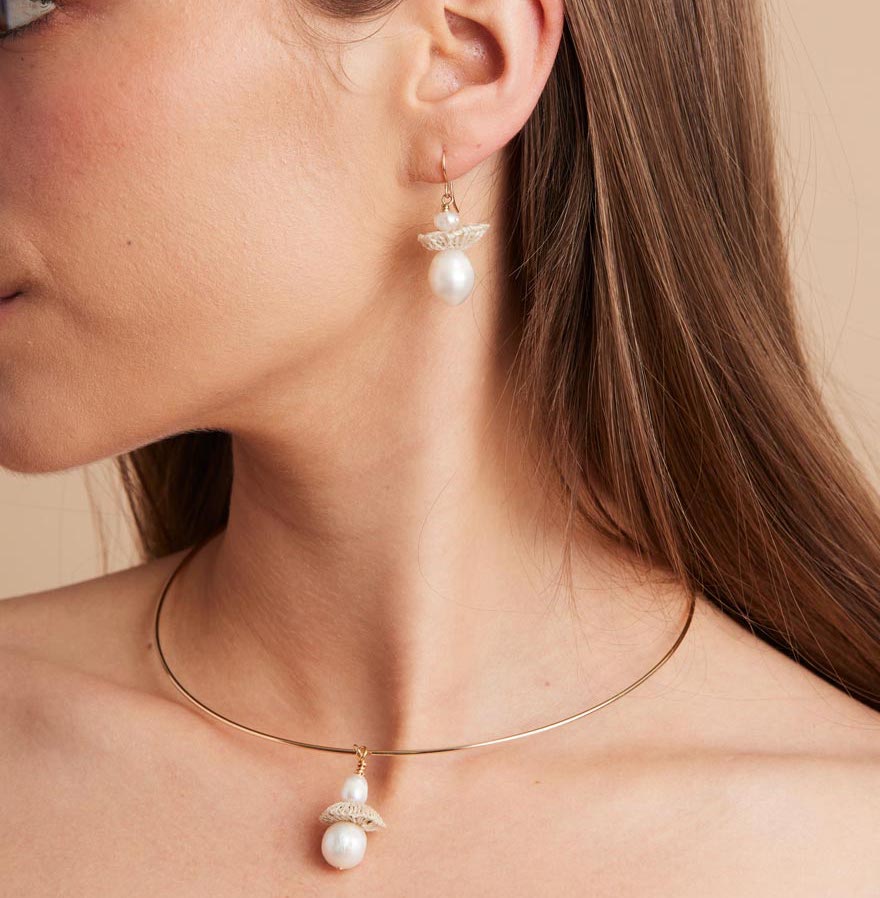Model wearing gold pearl drop earrings with matching choker