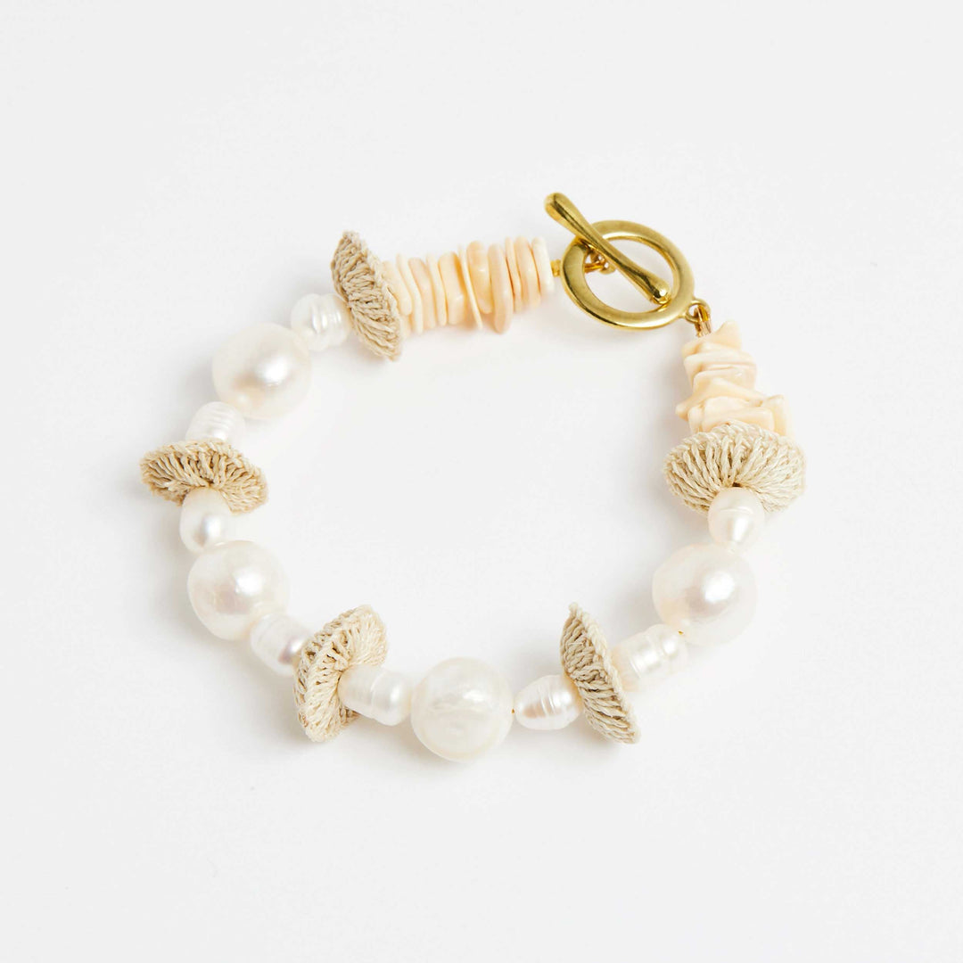 Side angle of pearl stack bracelet with pearls and natural fibre woven discs