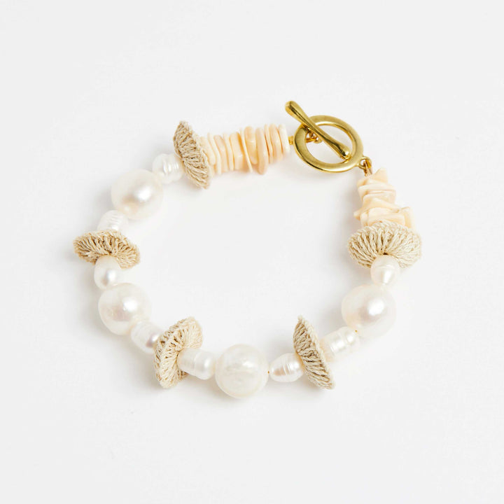 Side angle of pearl stack bracelet with pearls and natural fibre woven discs