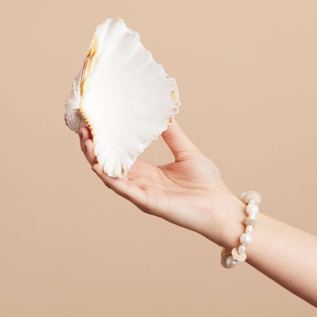 Still life with shell and pearl stack bracelet on wrist