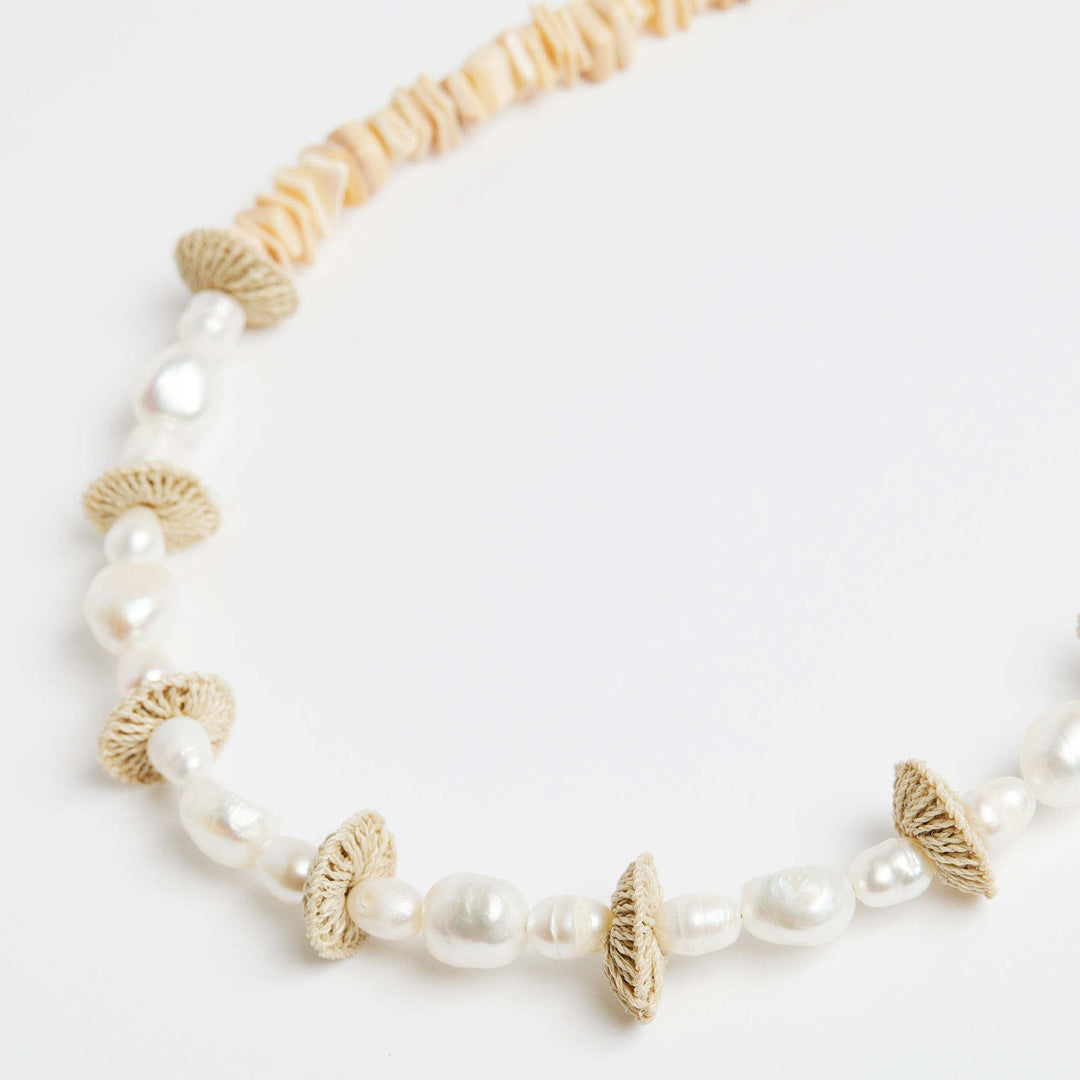Detail shot of the pearl stack necklace with pearls and natural fibre woven discs