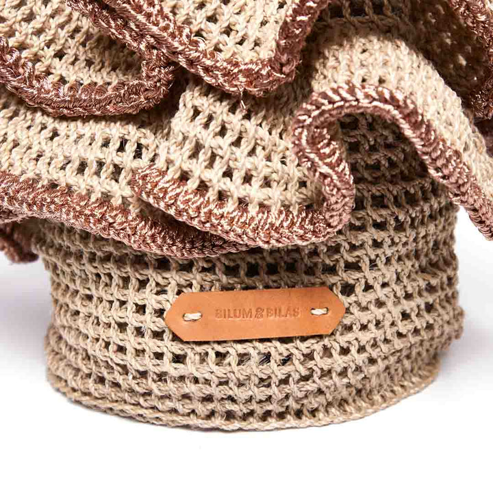 Detail of handwoven basket with woven ruffles with rose gold metallic trims.
