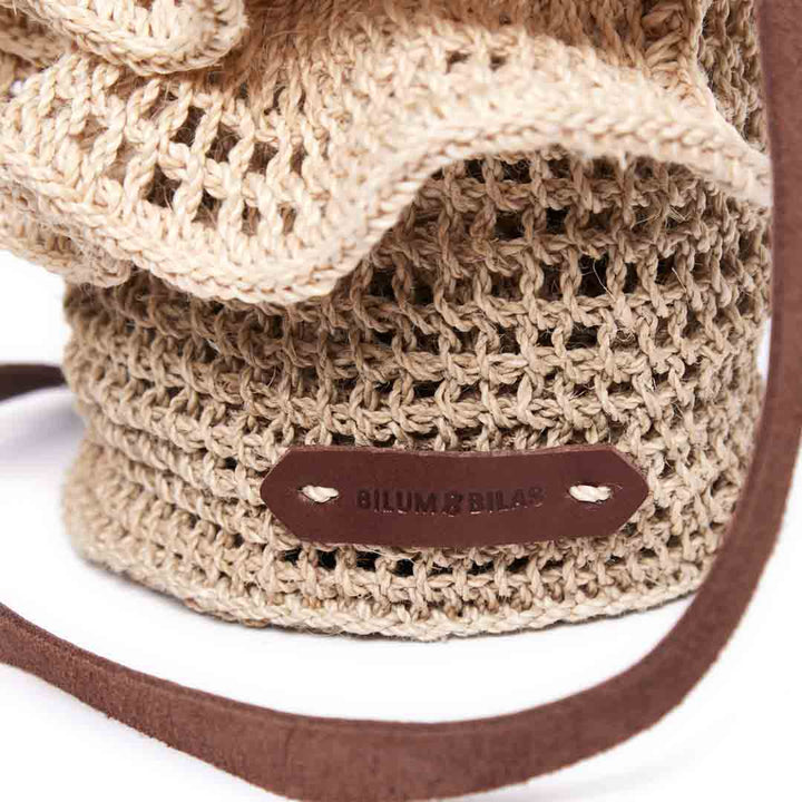 Detail of leather logo tag on the Ripple crossbody bag in natural.