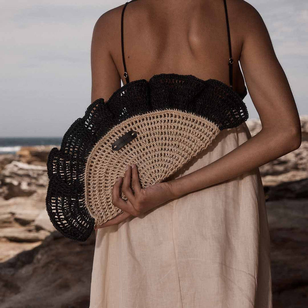 Close up of model holding the handwoven Ripple Clutch bag by Bilum and Bilas.