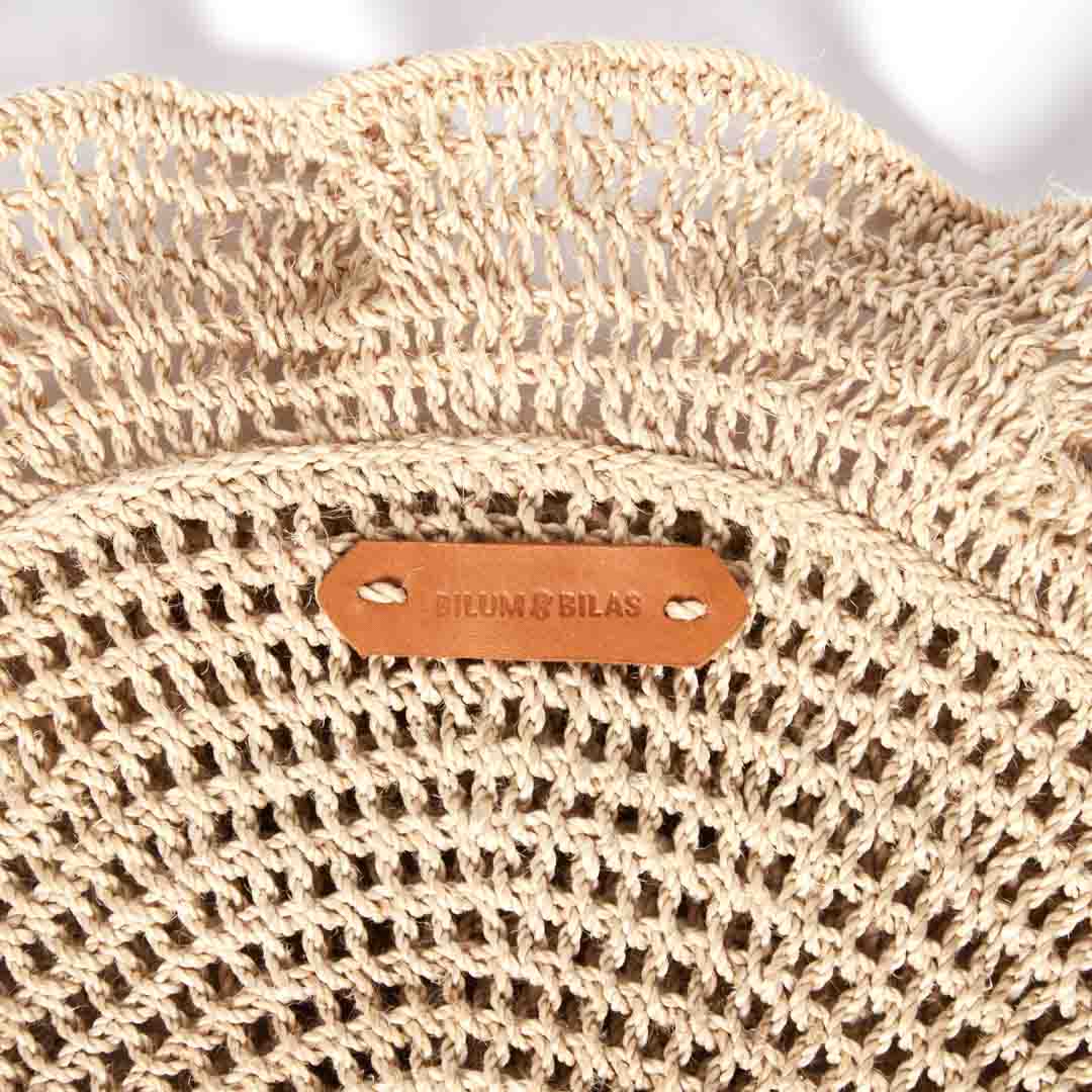 Detail on the woven ruffle on the ripple clutch bag in natural.