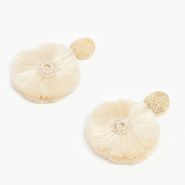 Natural fibre and gold disc pom pom earrings on an angle.