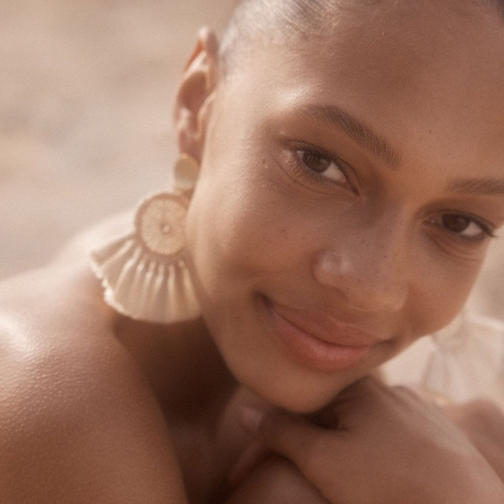 Woven disc earrings with fringing and gold disc on a model.