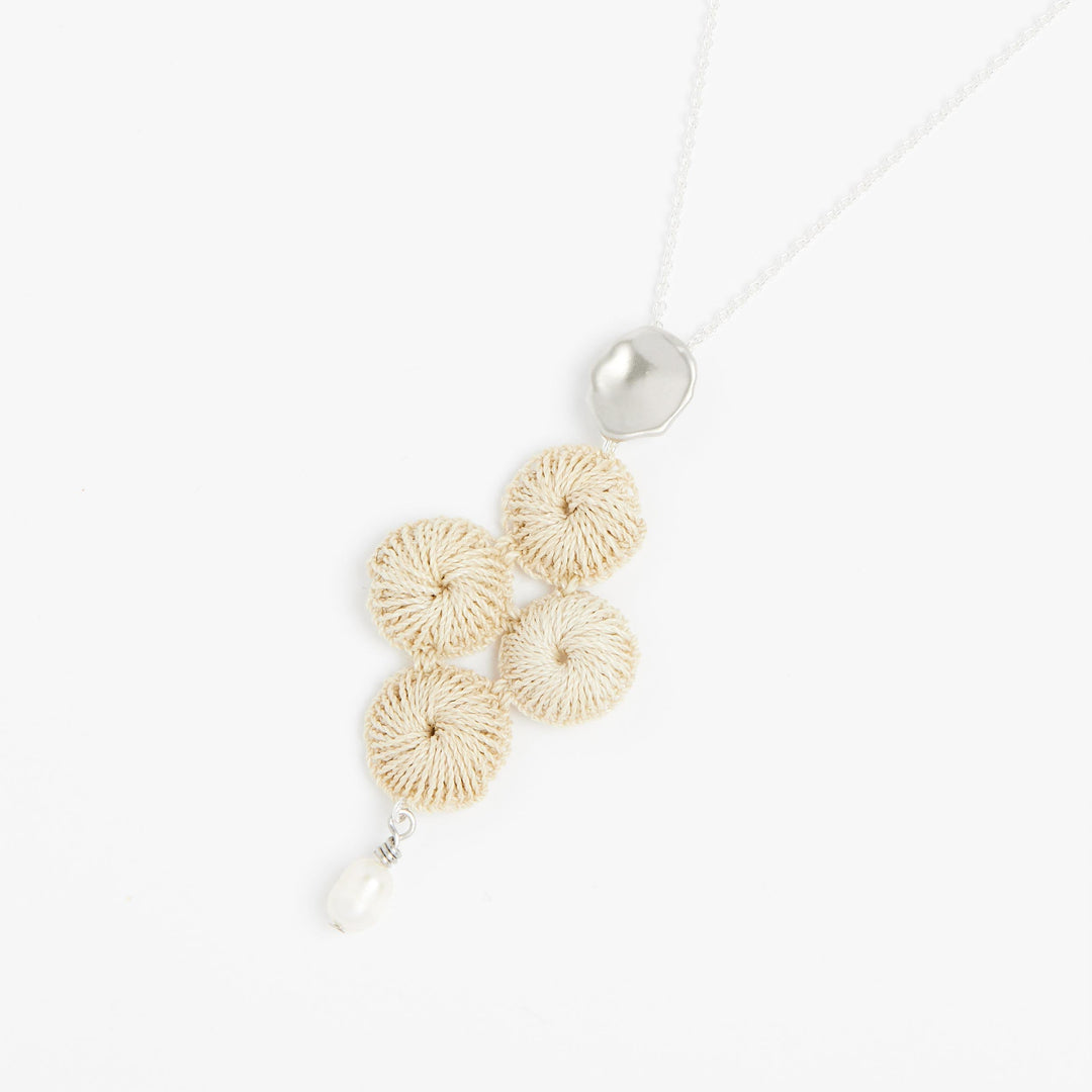 Side angle of sterling silver chain necklace with pearl and woven natural fibre pendant