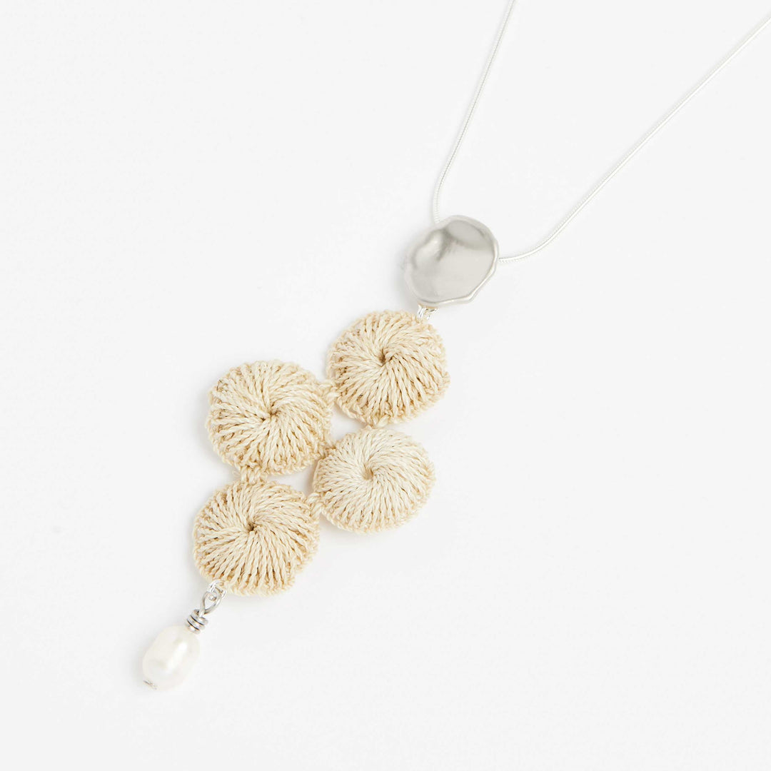 Side angle of sterling silver snake chain necklace with pearl and woven natural fibre pendant