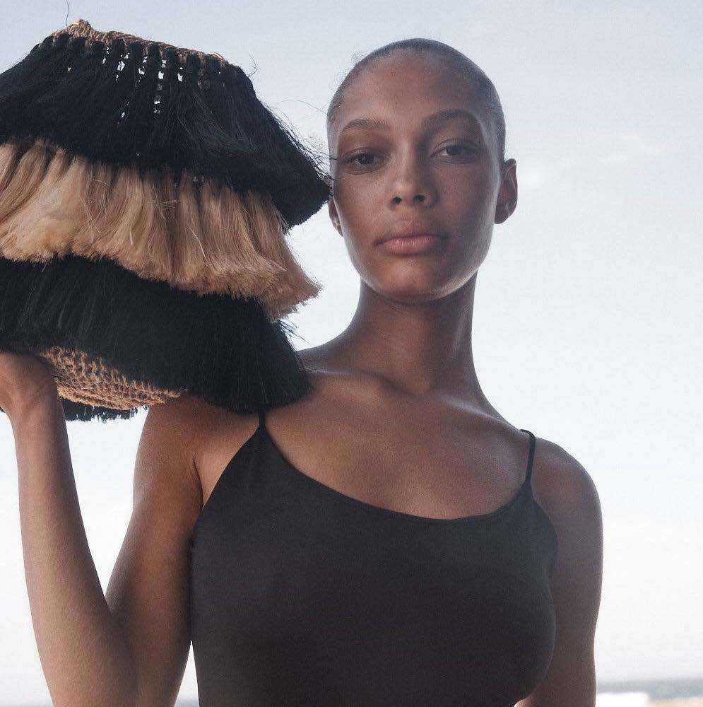 Modelled black and white tassel bag on beach.