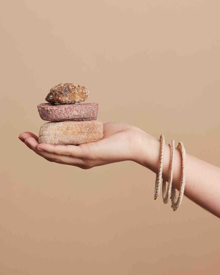 Still life with rocks with gold beaded Nambis luxury woven bangle set on wrist
