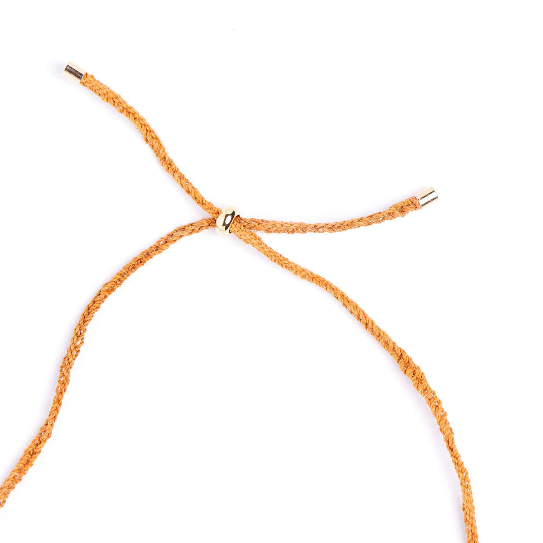 Orange braided bracelet with gold clasp on a white background