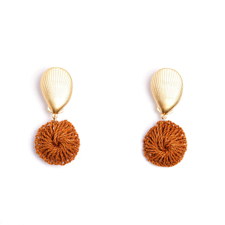Pair of earrings with gold teardrop tops and rust-colored pom-pom bottoms on a white background