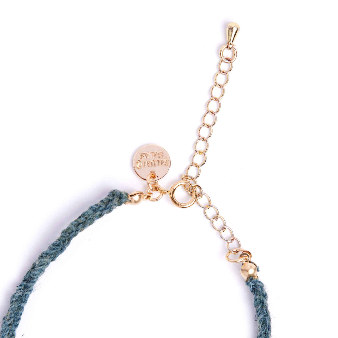 Bracelet with gold chain and blue cord on a white background