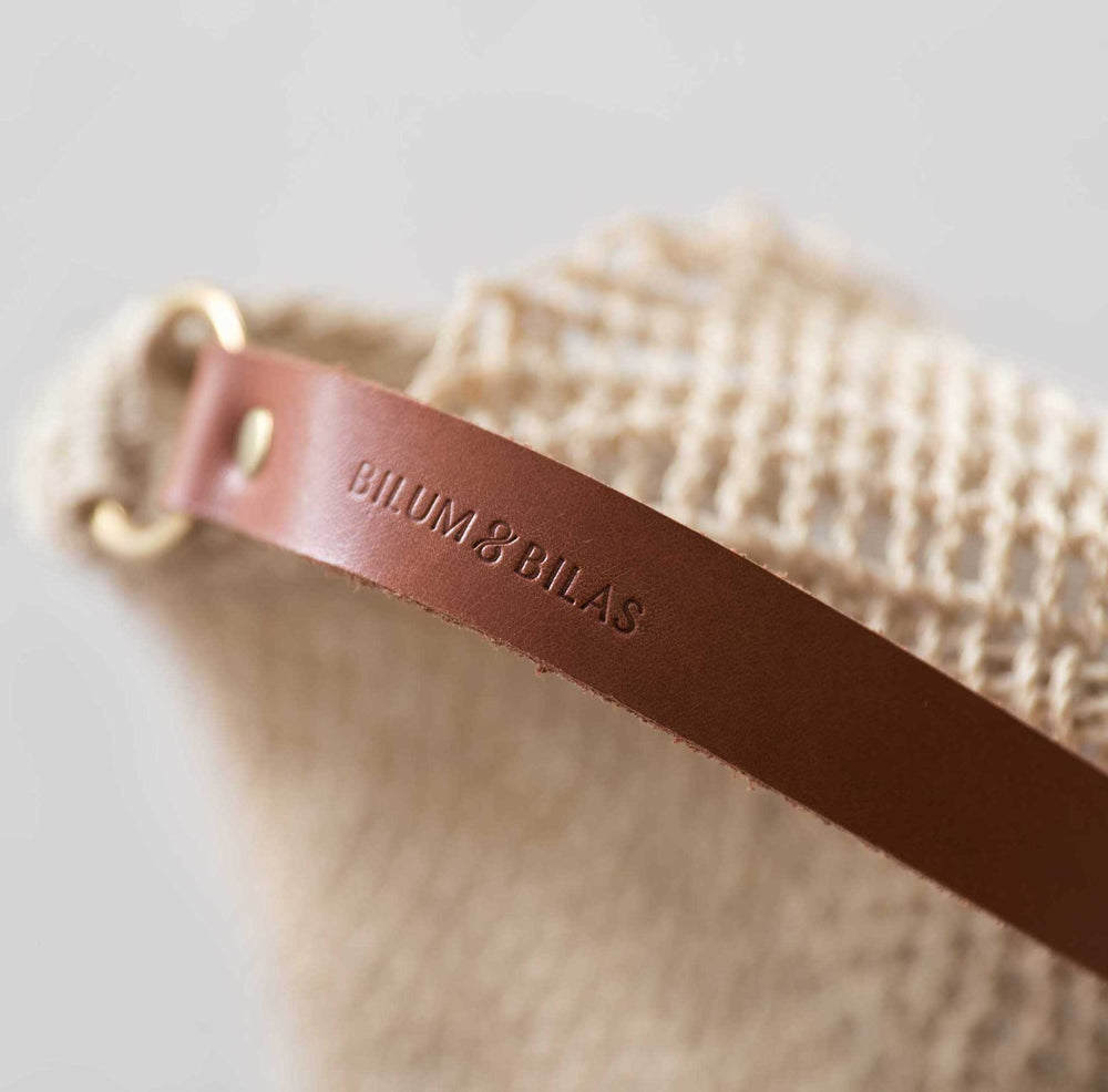 Bilum and Bilas Natural fibre woven bilum with a close up on the stamped logo on the leather straps