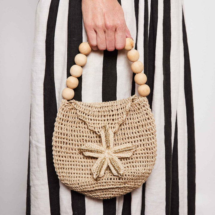 A woman holding mini woven bag in striped dress