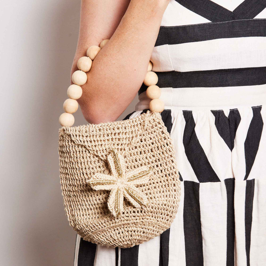 Woman holding woven mini bag with beaded handle