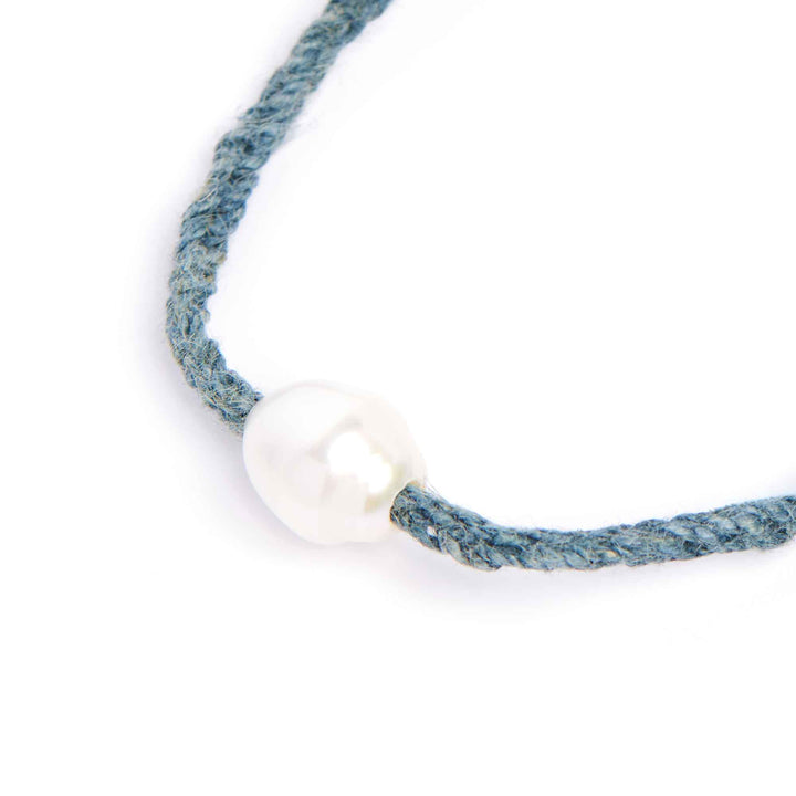 Necklace with a white bead on a blue cord against a white background