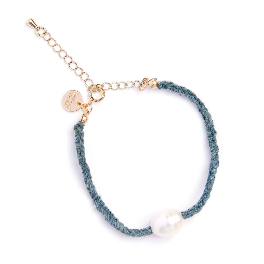 Bracelet with gold chain, blue cord, and pearl bead on a white background