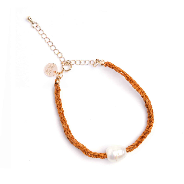 Brown braided bracelet with a pearl charm on a white background
