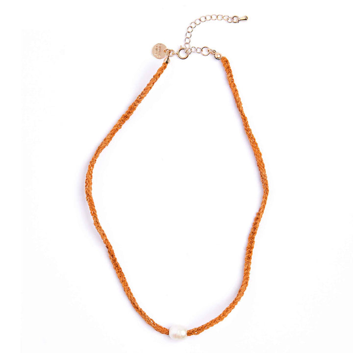 Orange necklace with a small heart charm on a white background